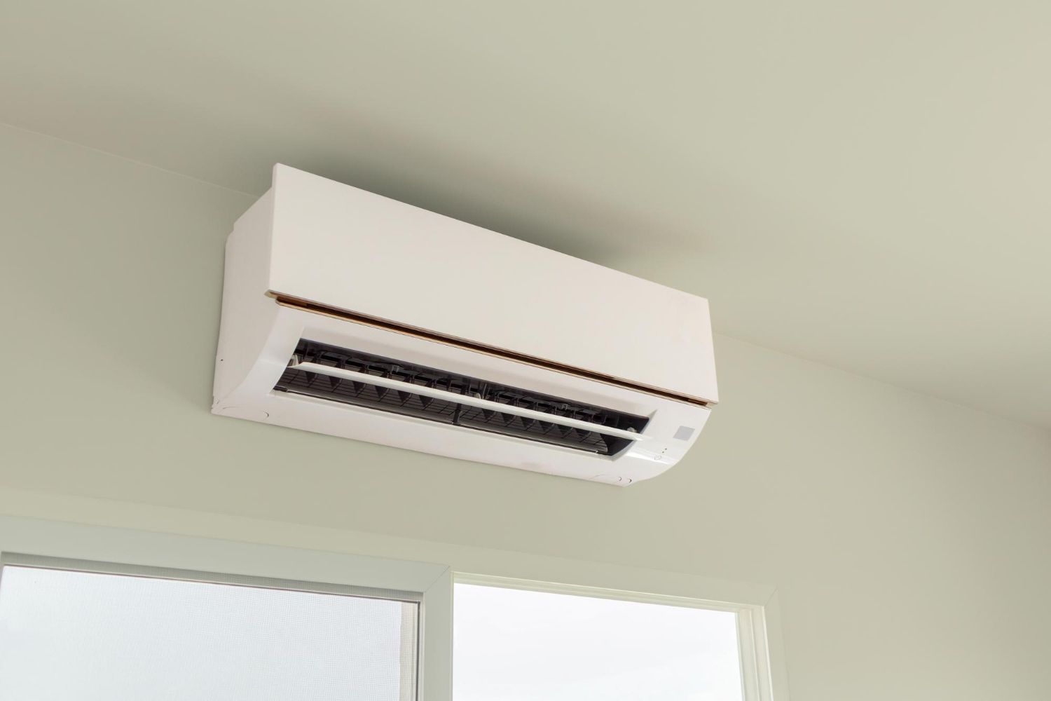 White wall-mounted air conditioner above a window.