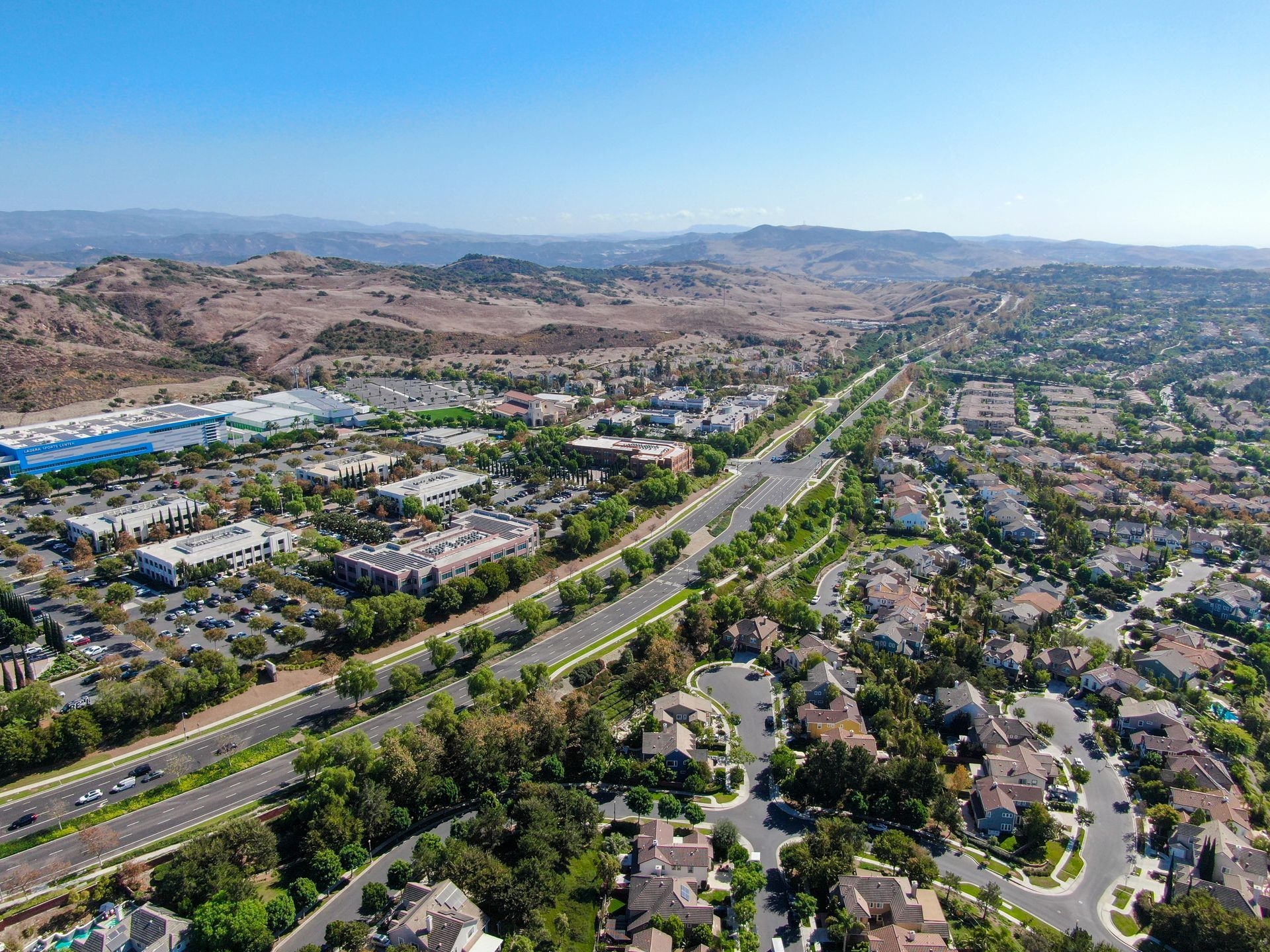 an aerial view of a residential area with a highway and mountains in the background .