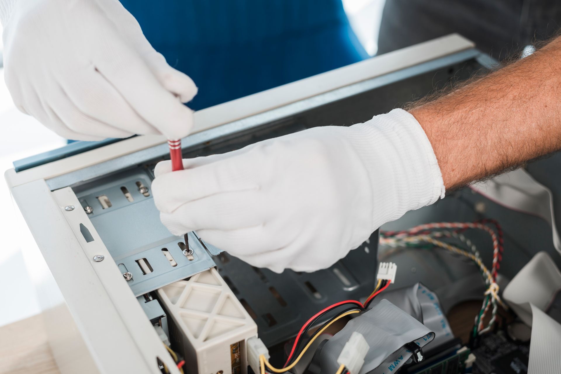 A man wearing white gloves is working on a computer.