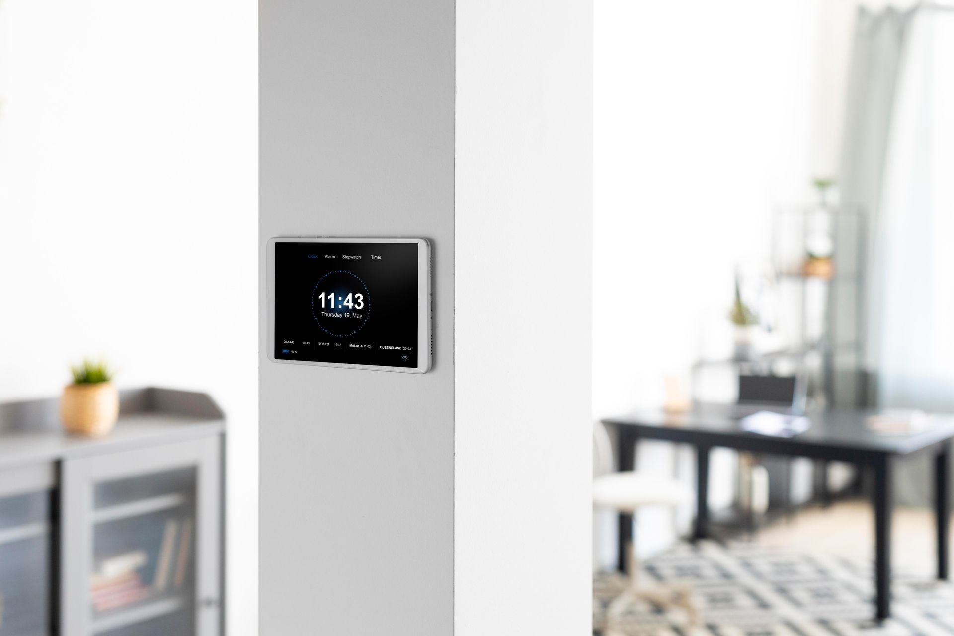 A smart thermostat is mounted on a wall in a living room.