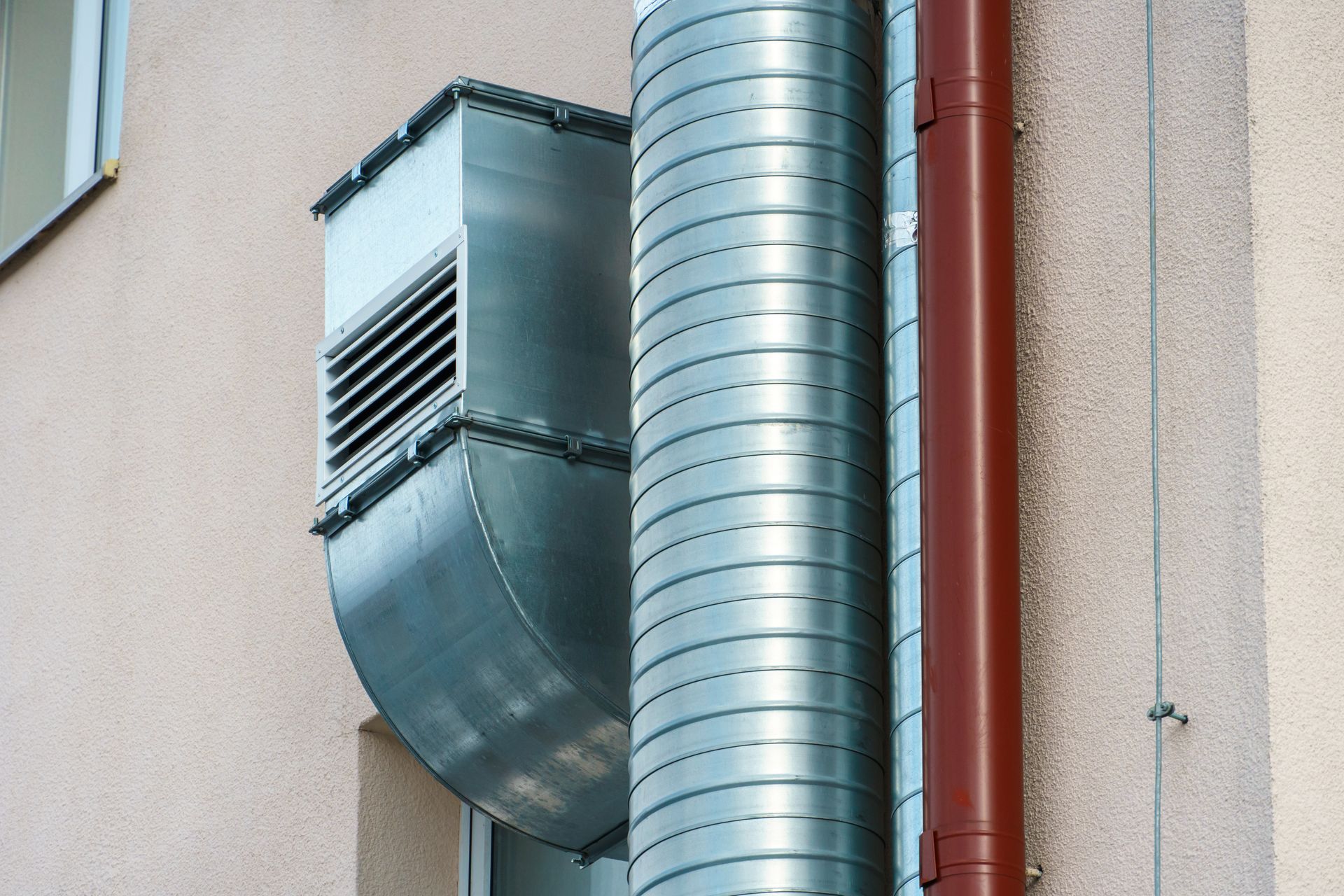 A metal pipe is attached to the side of a building.