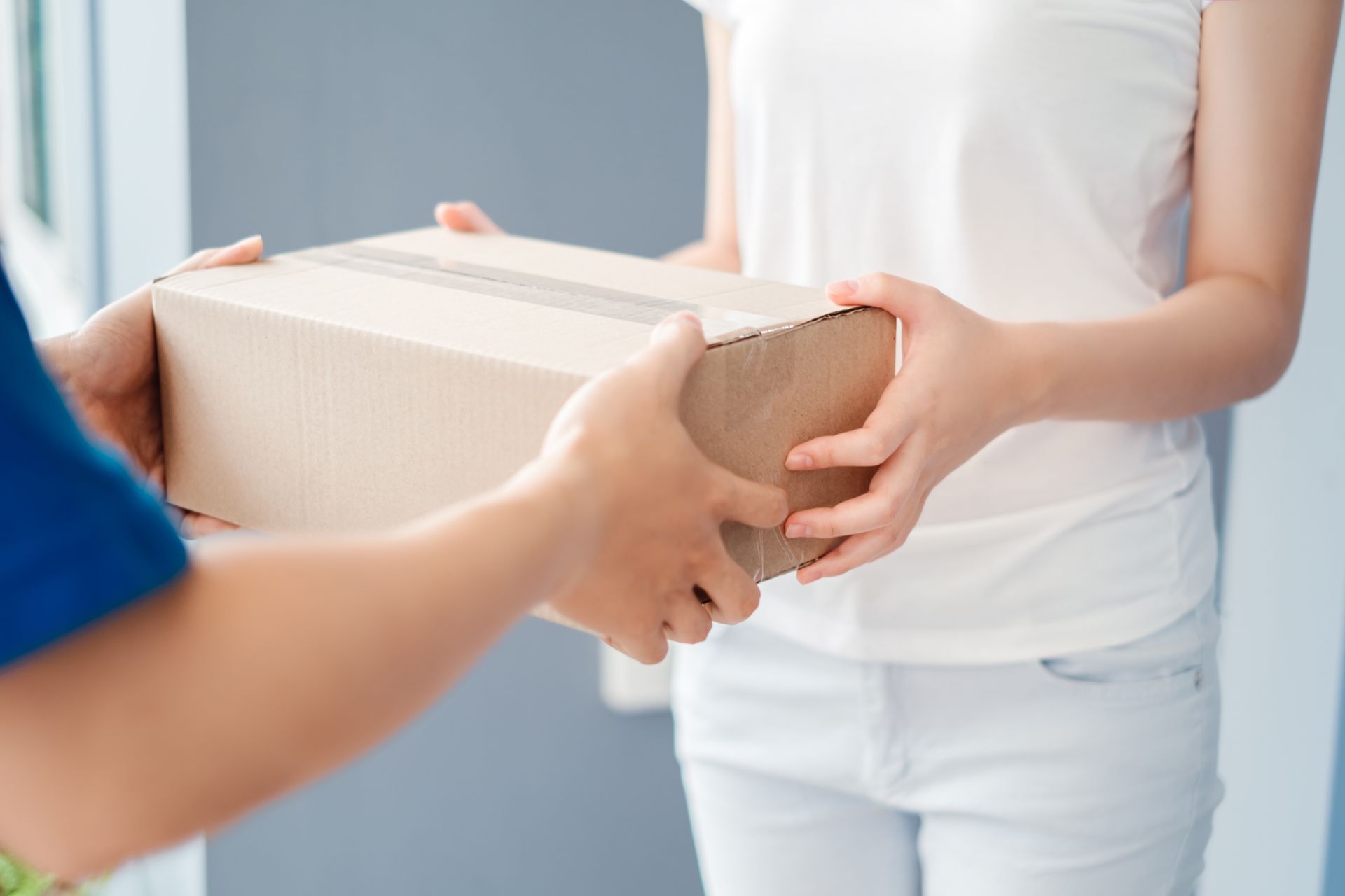 Man delivering a package to a woman with a zoom on the package itself. Man delivering a package to a woman with a zoom on the package itself.