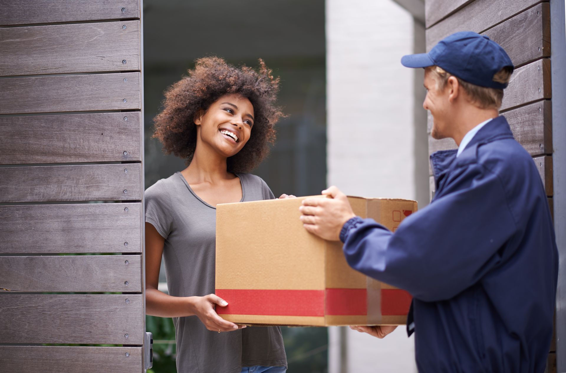 Woman receiving a delivery from a courier at her front door. Woman receiving a delivery from a courier at her front door.