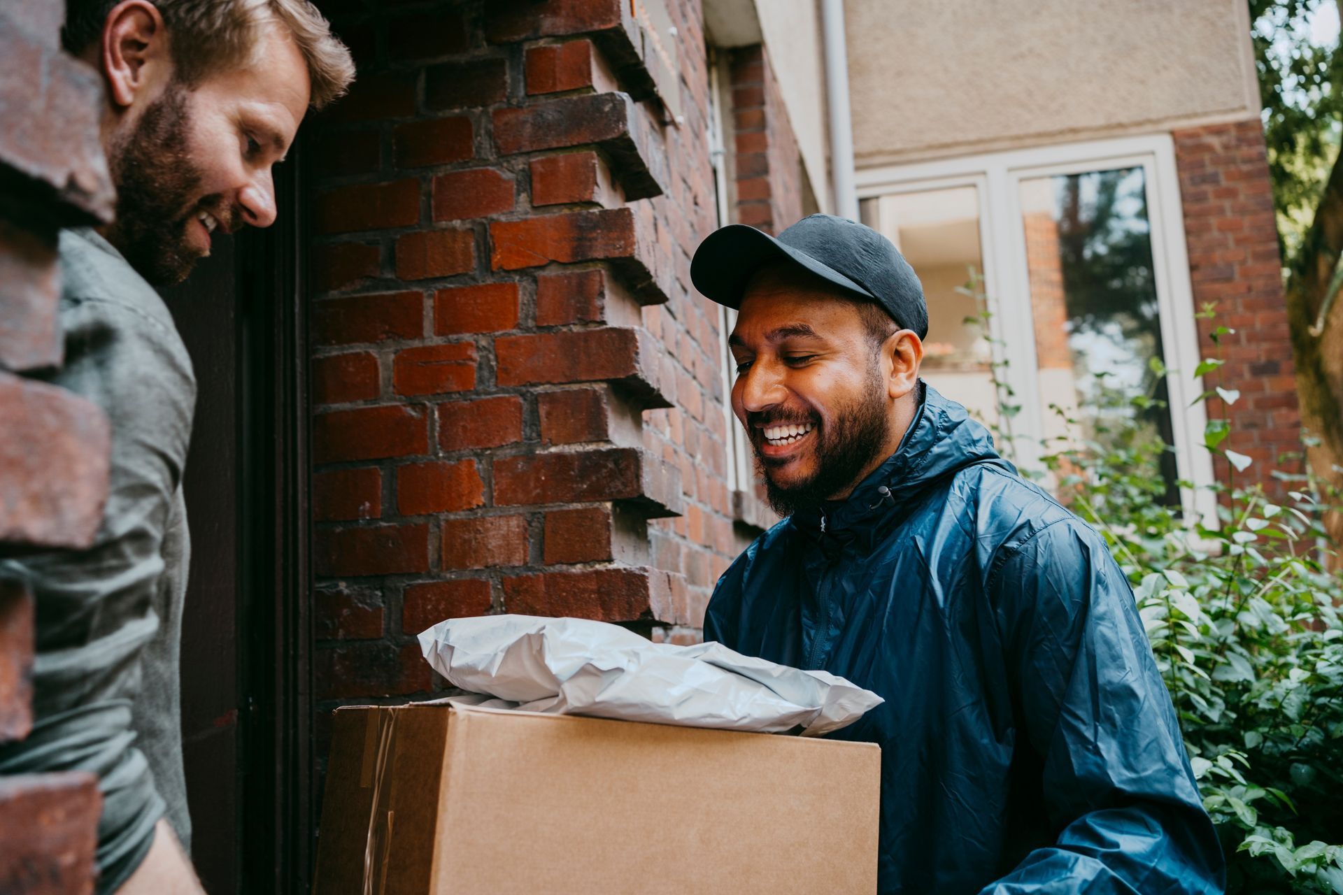 Smiling delivery man has just given a package to a businessman.