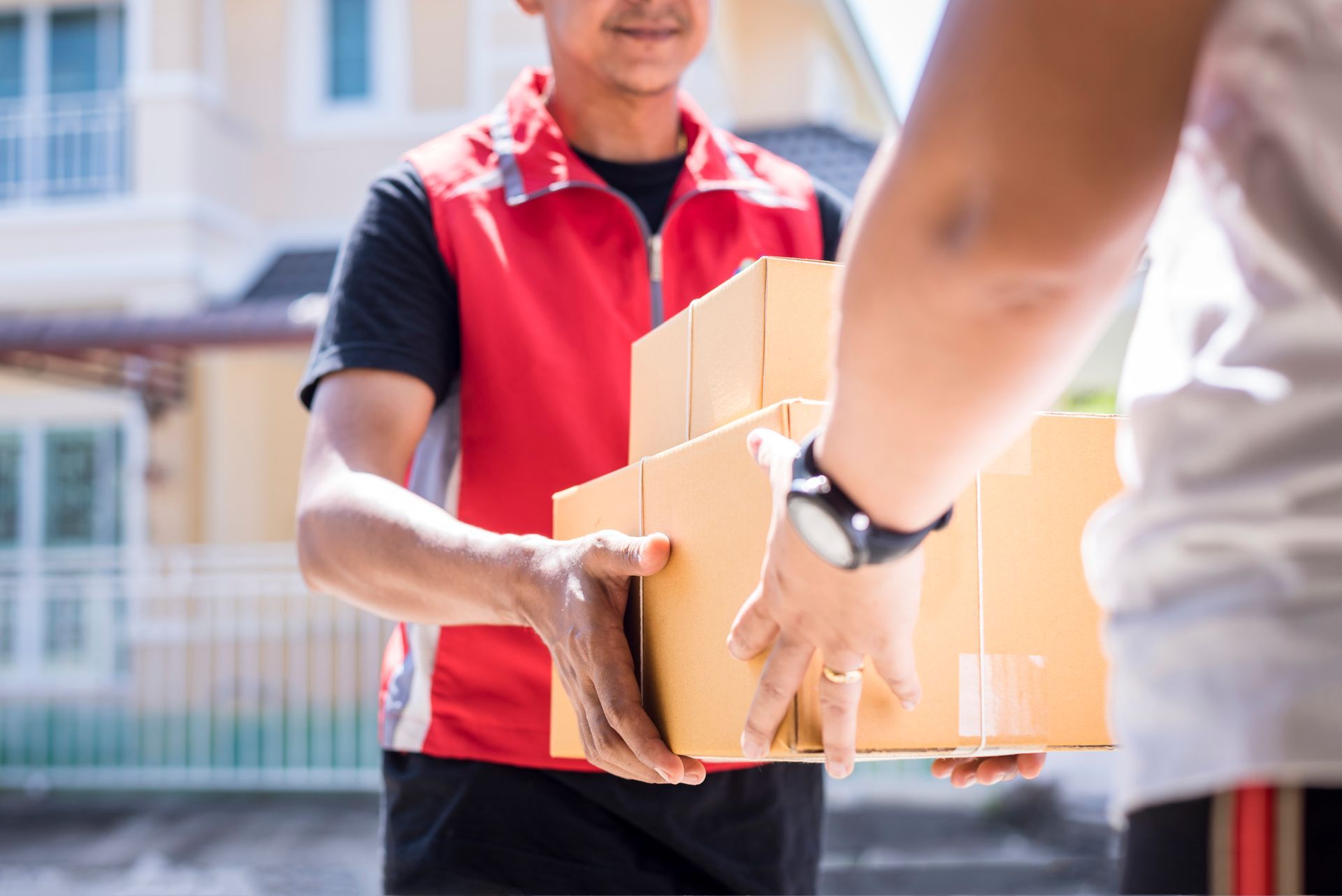 Courier handing cardboard boxes to customer during home delivery service.