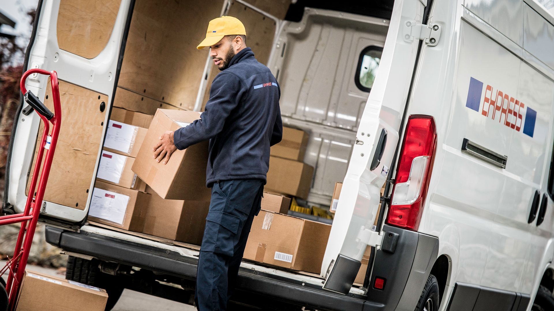 Delivery worker unloading cardboard boxes to a truck. Delivery worker unloading cardboard boxes to a truck.