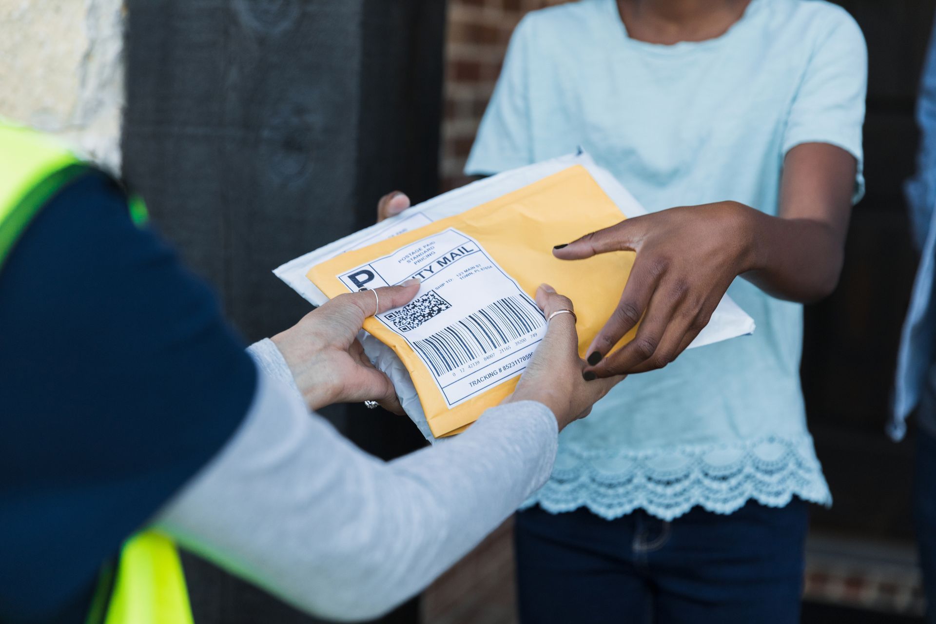 Delivery person in blue uniform hands package to woman at doorway. Delivery person in blue uniform hands package to woman at doorway.