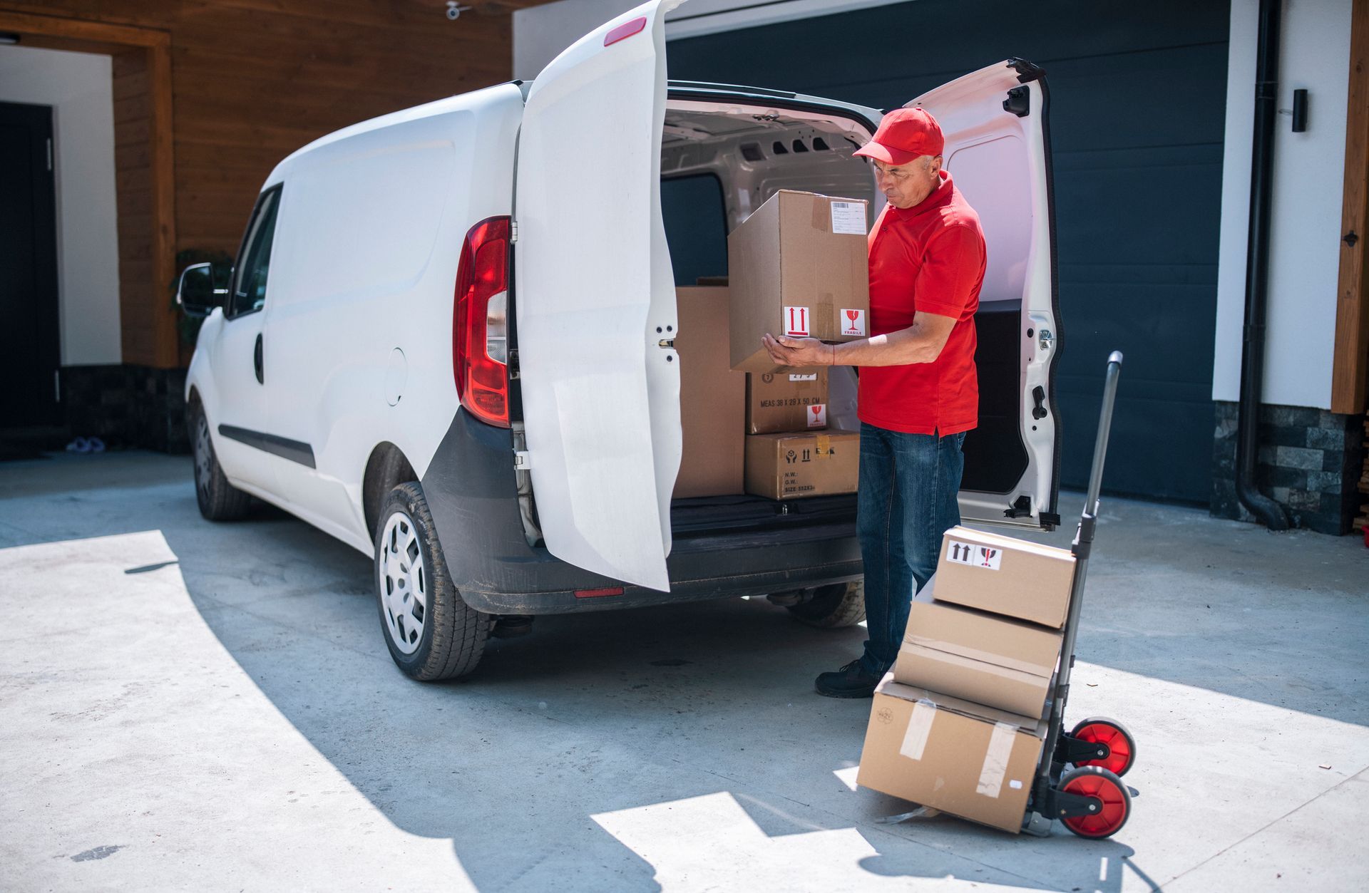 Airport workers loading cargo onto a plane. White cart, blue sky, bright vests.