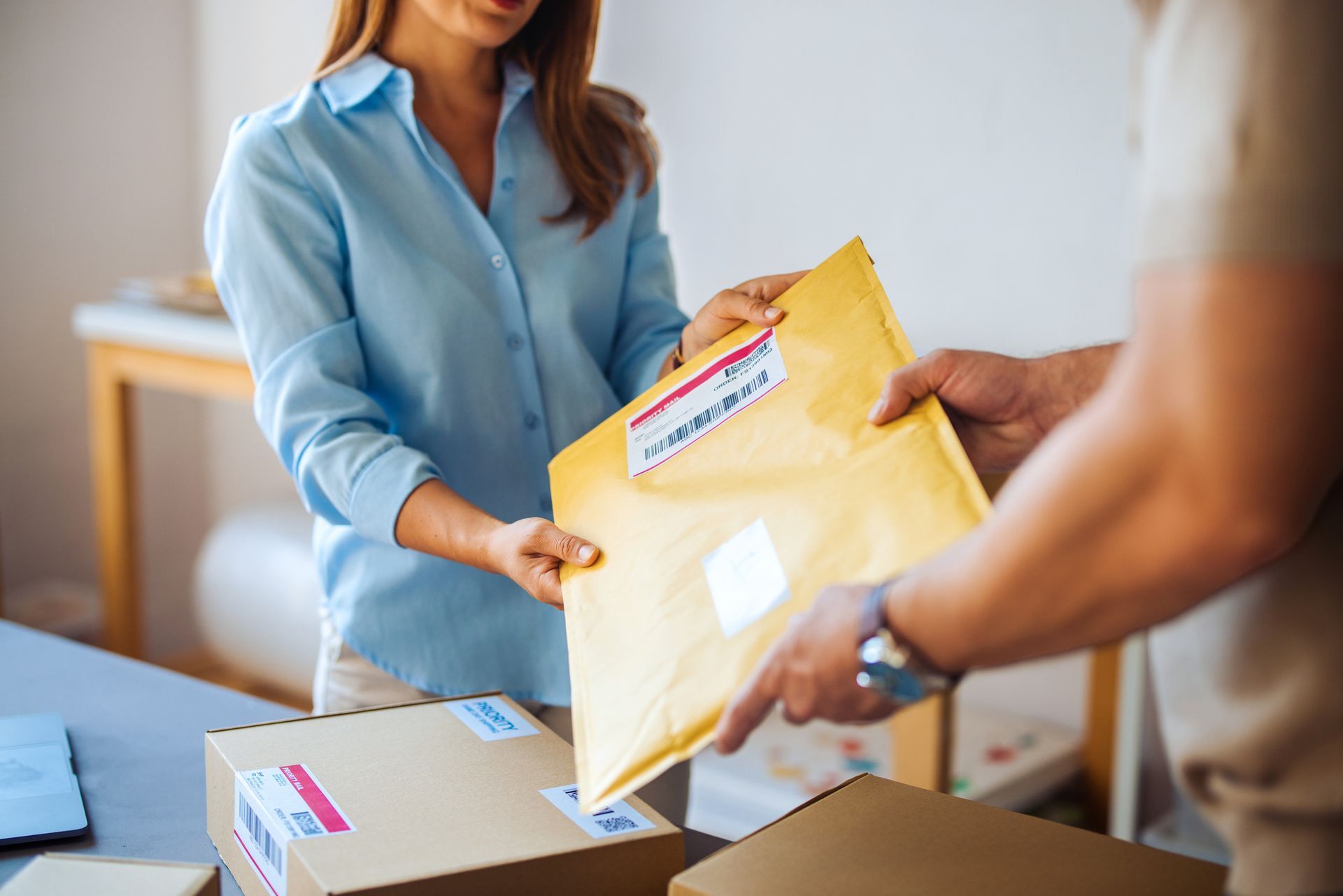 Delivery person in blue uniform handing packages to a person in a light blue shirt.