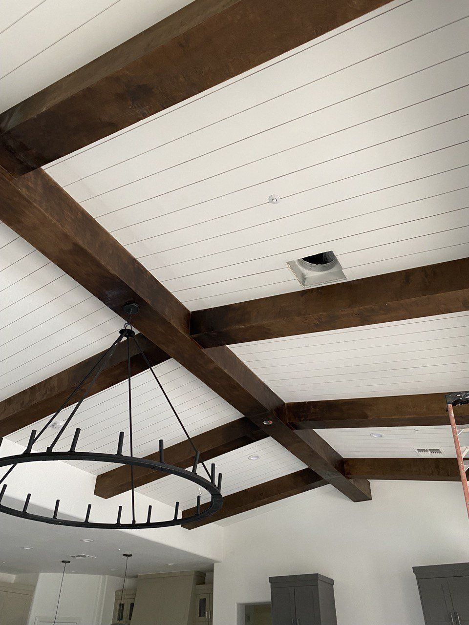 A ceiling with wooden beams and a chandelier hanging from it.