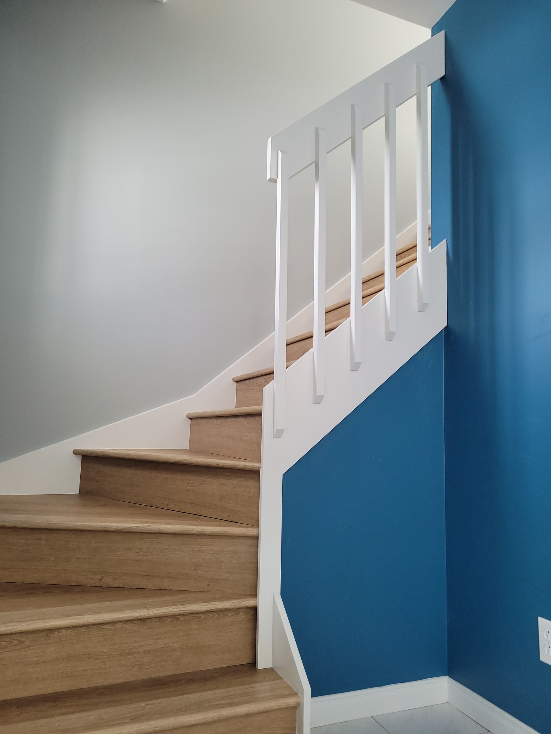 Un escalier en bois avec une rampe blanche et des murs bleus
