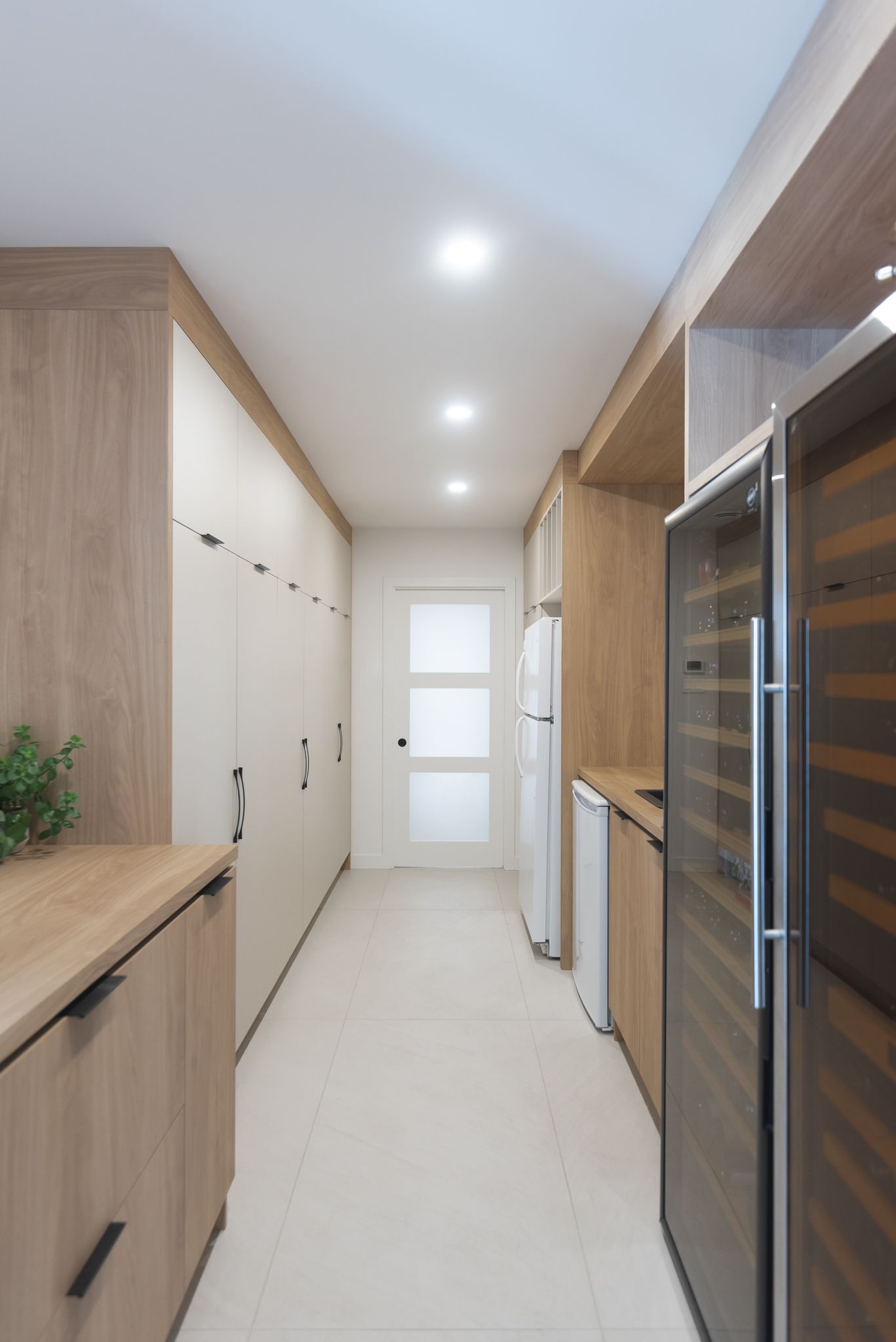 Un long couloir dans une cuisine avec des armoires en bois et une cave à vin.