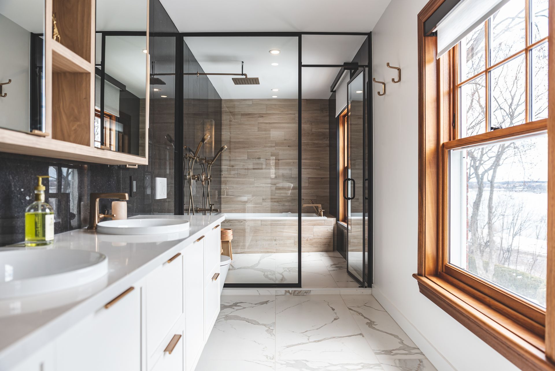 Une salle de bain avec deux lavabos, une baignoire, une douche et une fenêtre.