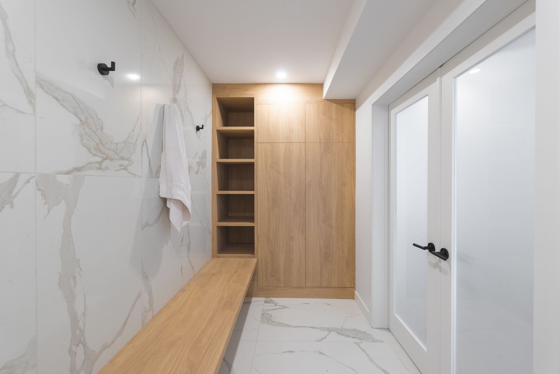 Un couloir avec un banc en bois et un mur en marbre.