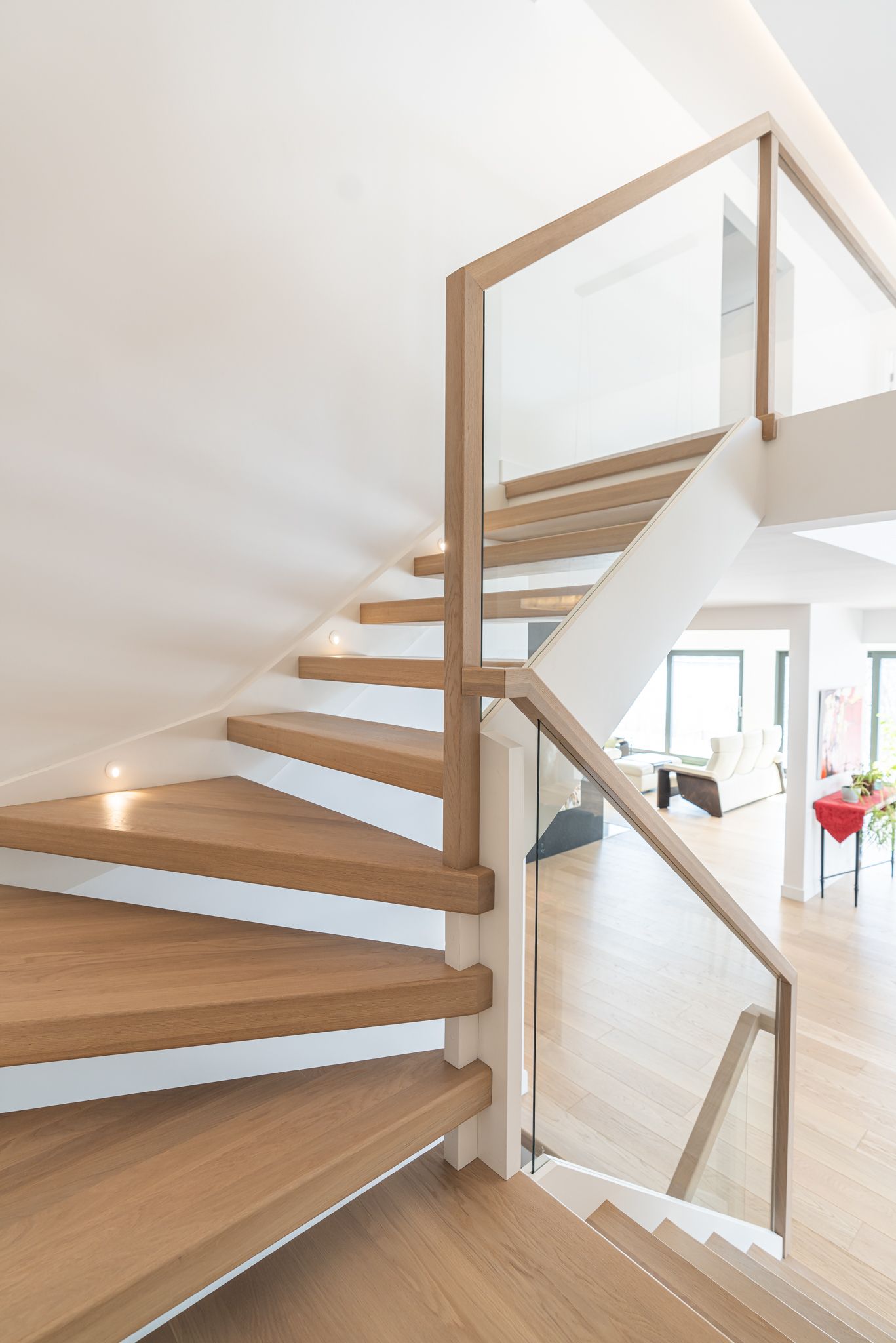 Un escalier en bois avec une rampe en verre dans une maison.