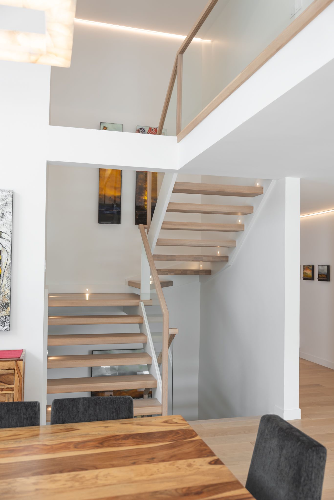 Une salle à manger avec une table et des chaises en bois et des escaliers