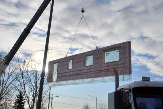 Une grue soulève un gros morceau de bois dans les airs.