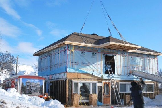Un homme se tient devant une maison en construction.