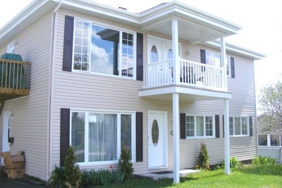 Une grande maison blanche avec des volets noirs et un balcon