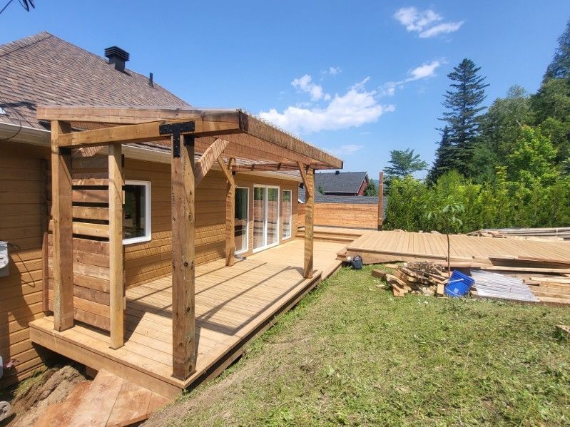 Une terrasse en bois est en cours de construction dans la cour d'une maison.