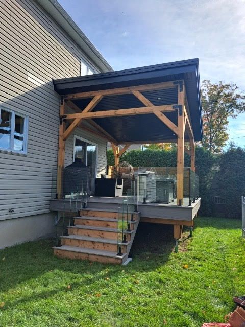 Une terrasse en bois avec des escaliers qui y mènent se trouve dans la cour d'une maison.