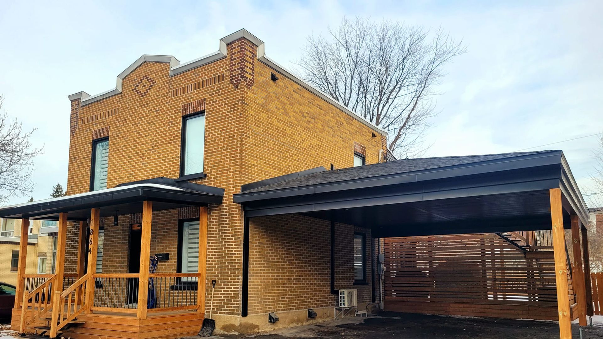 Une maison en brique avec un porche et un abri d'auto.