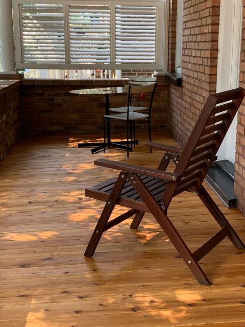 Une chaise en bois est posée sur un plancher en bois devant un mur de briques.