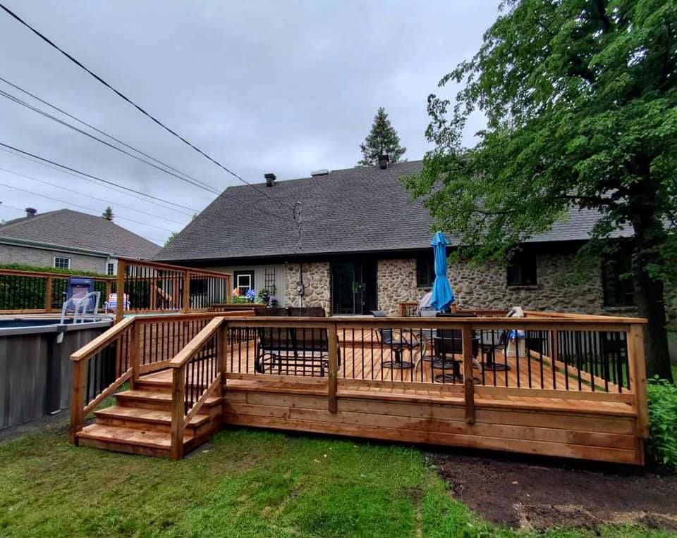 Une grande terrasse en bois se trouve dans la cour d'une maison.