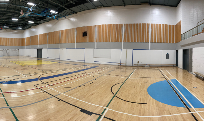 Un grand terrain de basket couvert avec un parquet en bois.