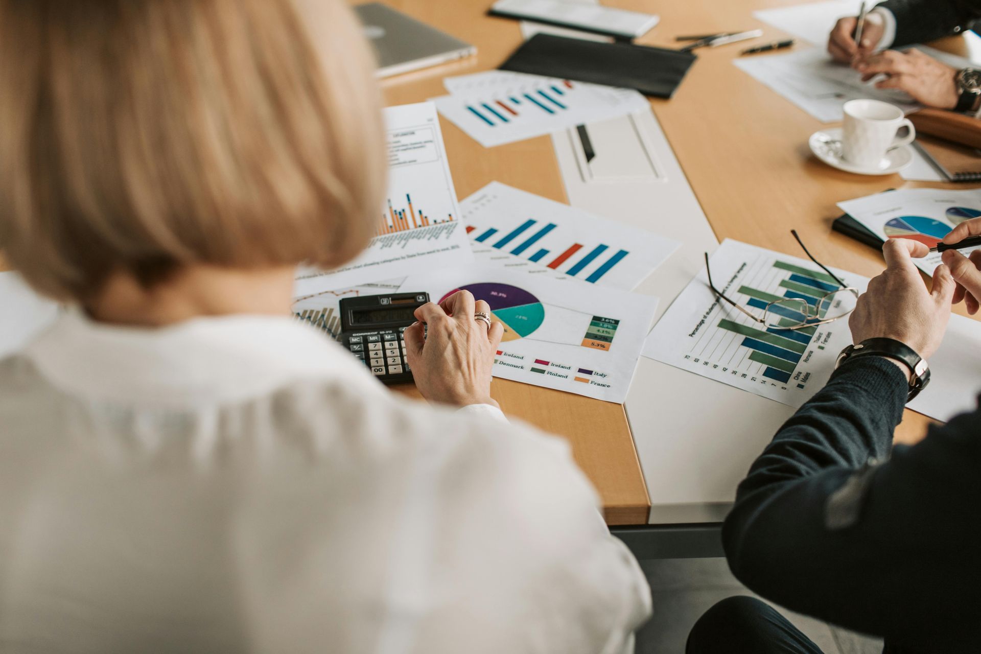 People reviewing financial charts and documents at a wooden table.