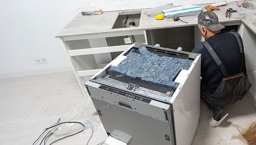 A man is installing a dishwasher in a kitchen.