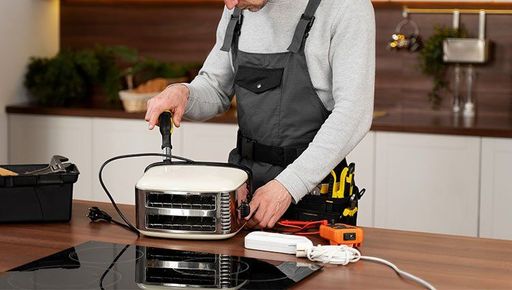 A man is fixing a toaster oven in a kitchen.