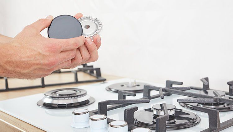 A person is holding a gas burner on top of a stove.