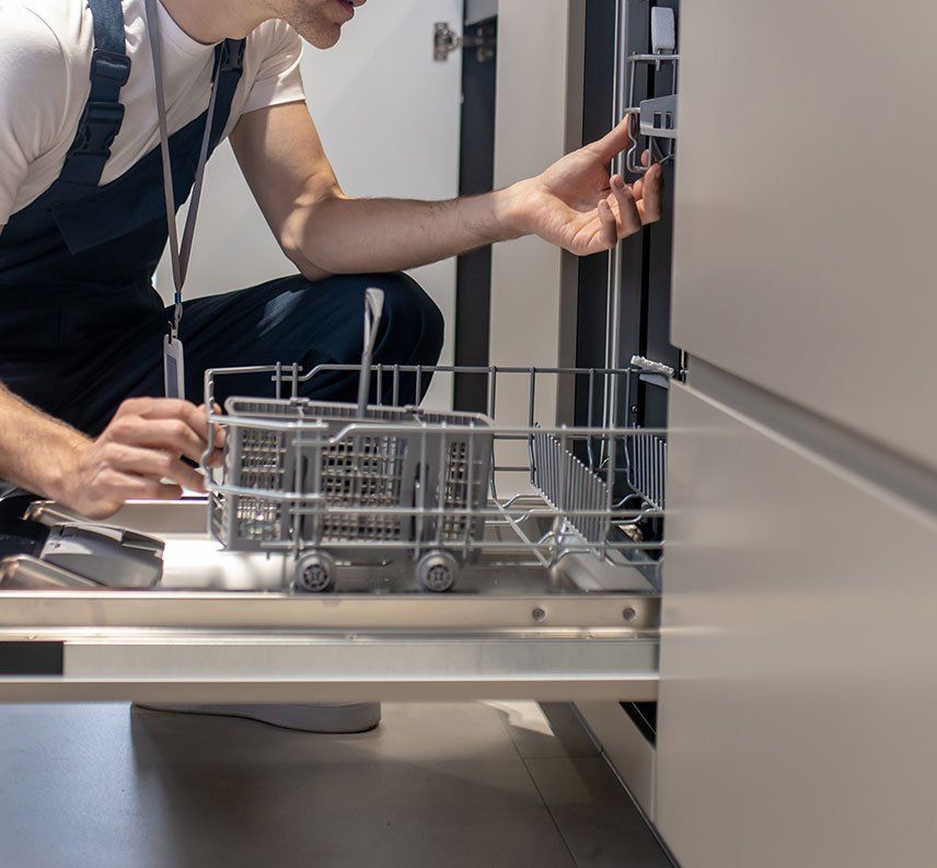 A man is working on a dishwasher in a kitchen