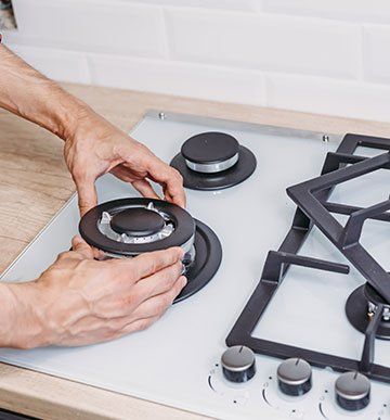 A person is adjusting the burners on a gas stove.