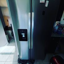 A stainless steel refrigerator is sitting in a kitchen next to a door.