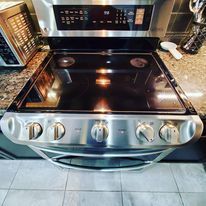 A stainless steel stove top oven is sitting on top of a granite counter in a kitchen.