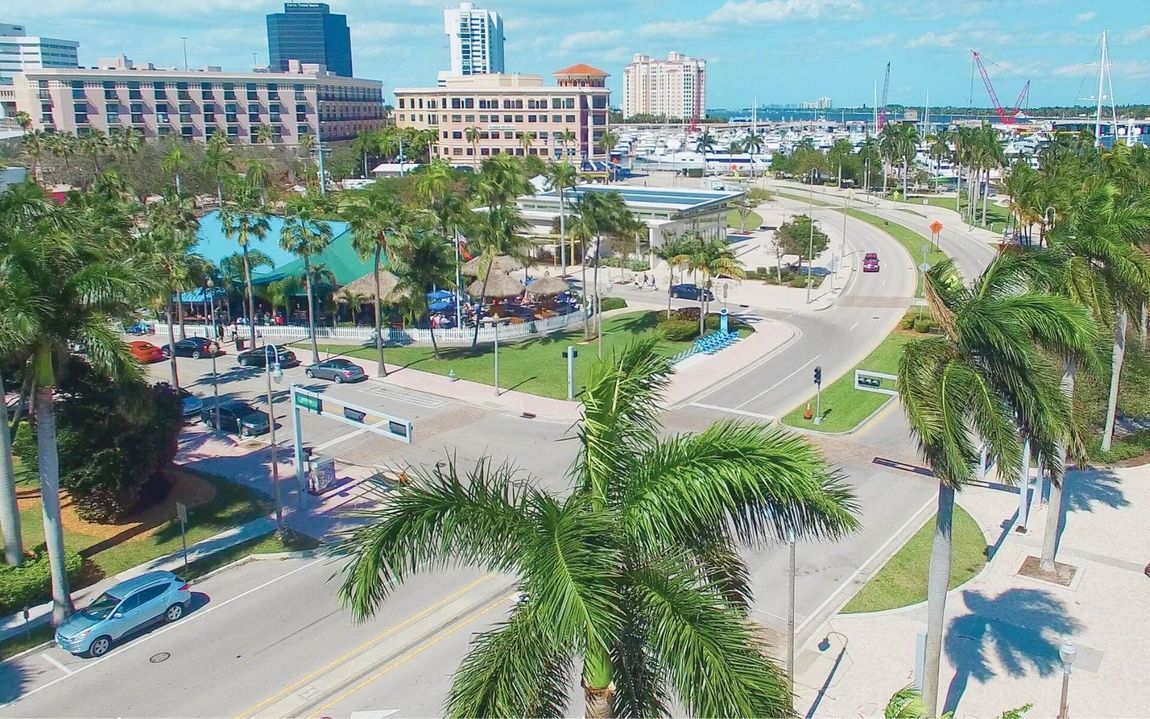 An aerial view of a city street with palm trees and cars driving down it.