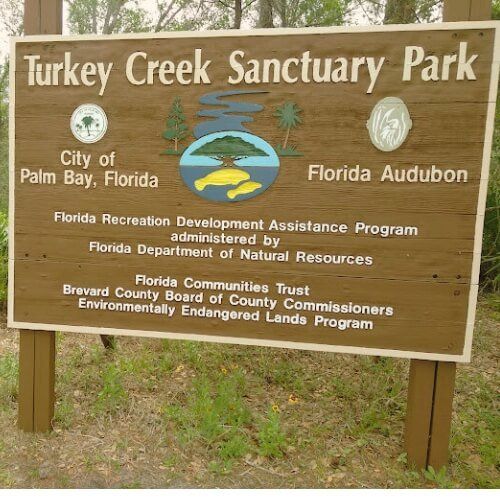 A wooden sign for turkey creek sanctuary park