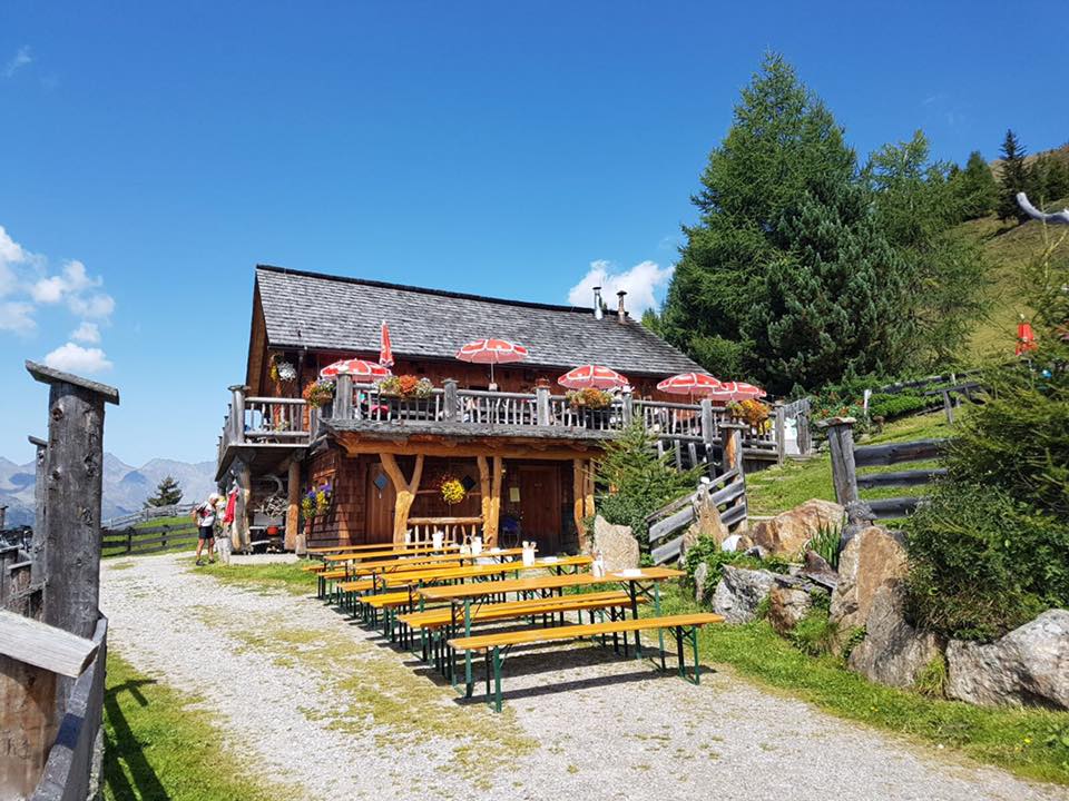 Ein großes Holzgebäude mit vielen Bänken davor.