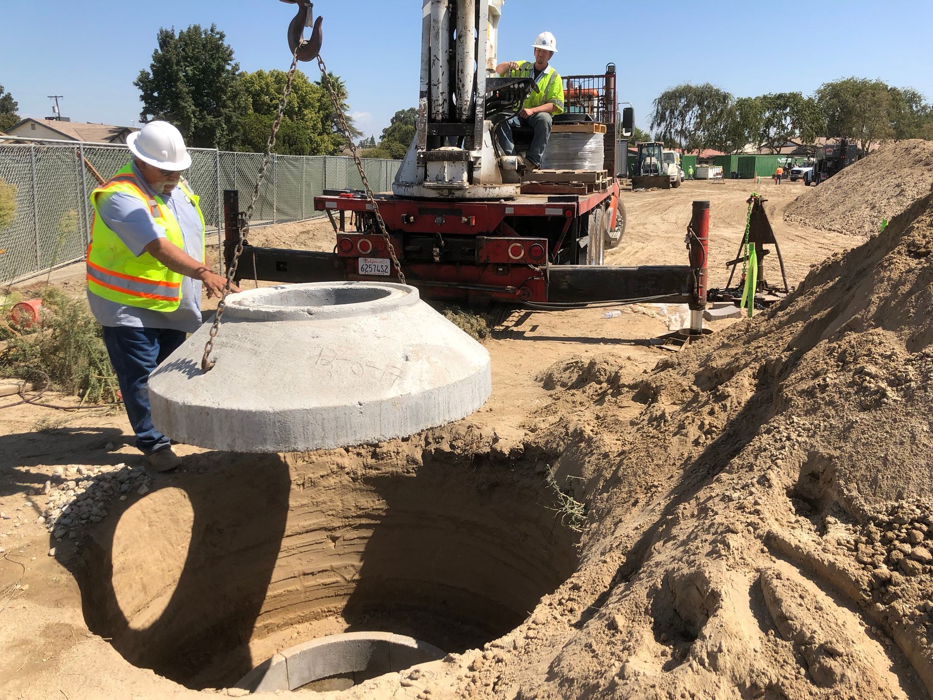 Crew lowering precast concrete drain cap into place during stormwater system install in Reedley, CA