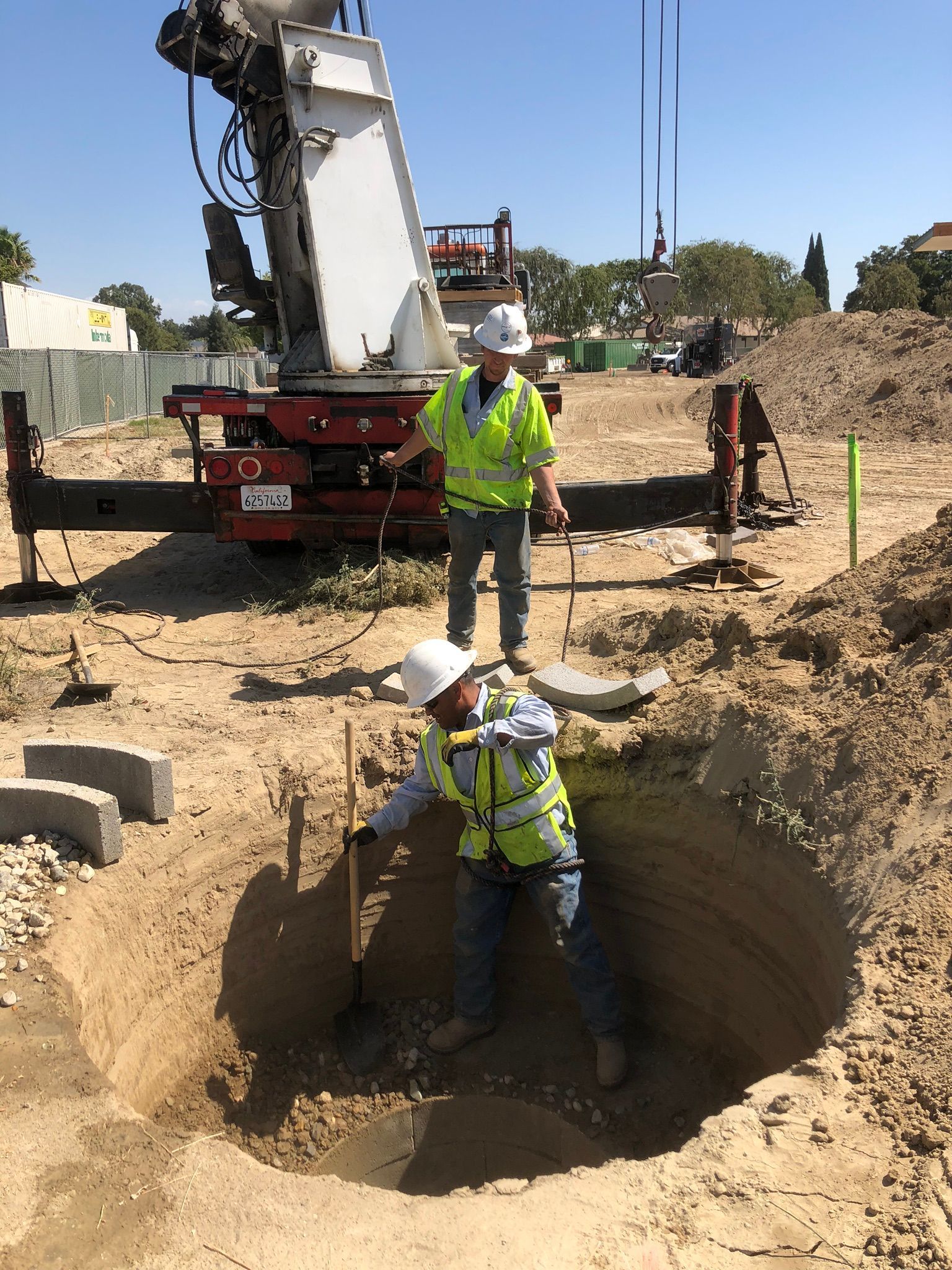 Crew backfilling and compacting media around area drain vault during installation in Reedley, California