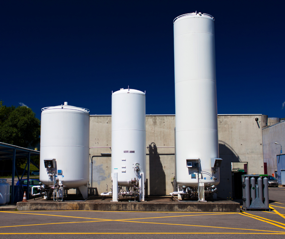 Three white tanks are lined up in front of a building