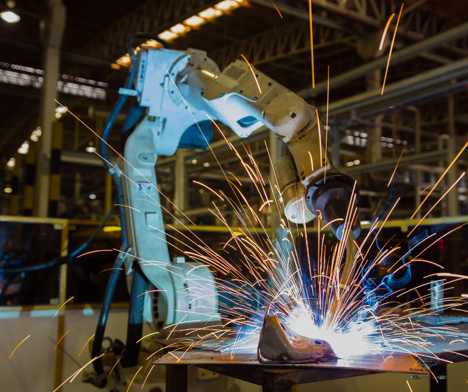 Robotic arm performing automated welding with bright sparks inside a Detroit facility.