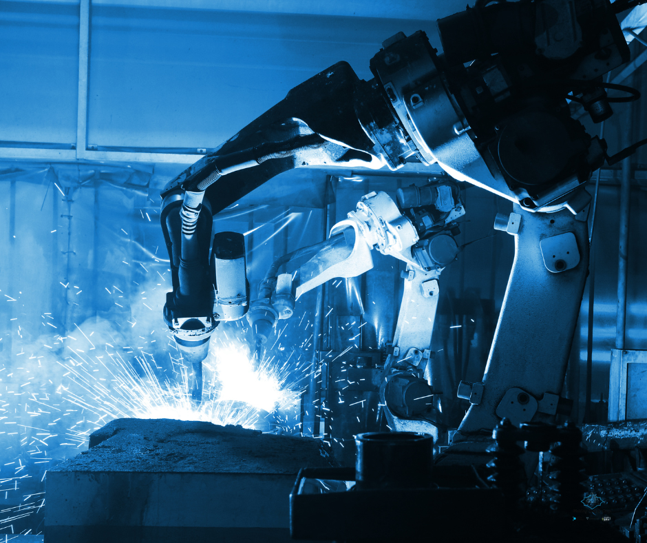 Robotic arm performing welding in an industrial setting, with sparks flying from the welding process