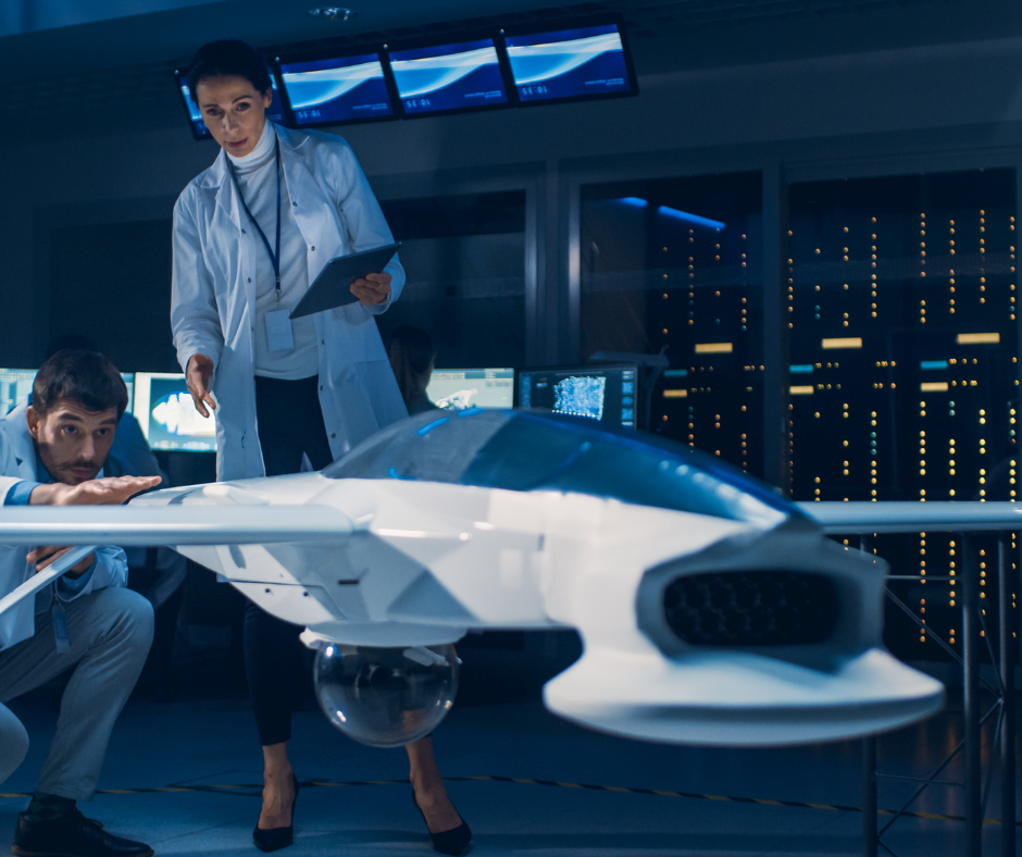 The image depicts a dynamic aerospace engineering scene where a team of professionals is actively engaged in analyzing a futuristic aircraft model. A female engineer in a white lab coat, holding a digital tablet, is pointing out specific features on the model to her colleague. The male engineer is closely examining the aircraft, indicating a moment of focused collaboration. They are surrounded by sophisticated equipment and large computer servers, indicative of a high-tech laboratory environment. The atmosphere is one of intense concentration and technical discussion, reflecting the cutting-edge nature of aerospace innovation.