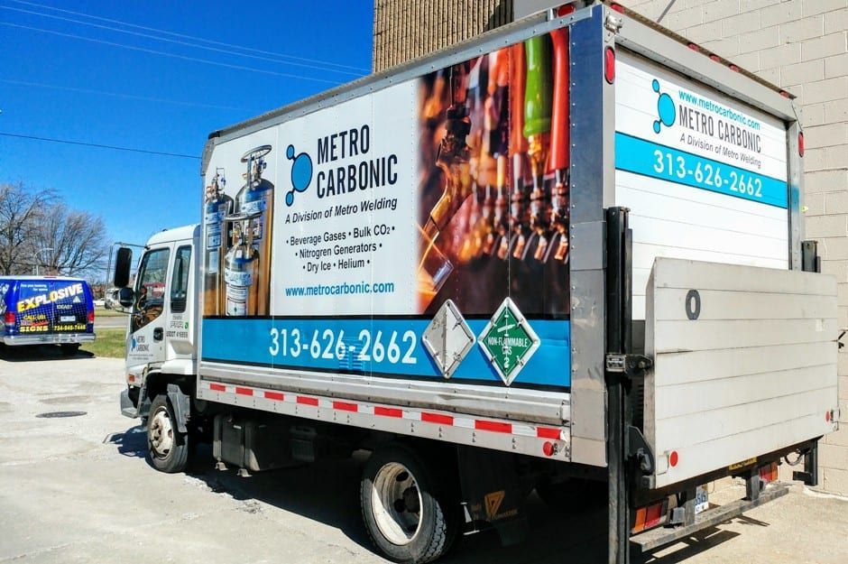 A metro carbonic truck is parked in a parking lot.