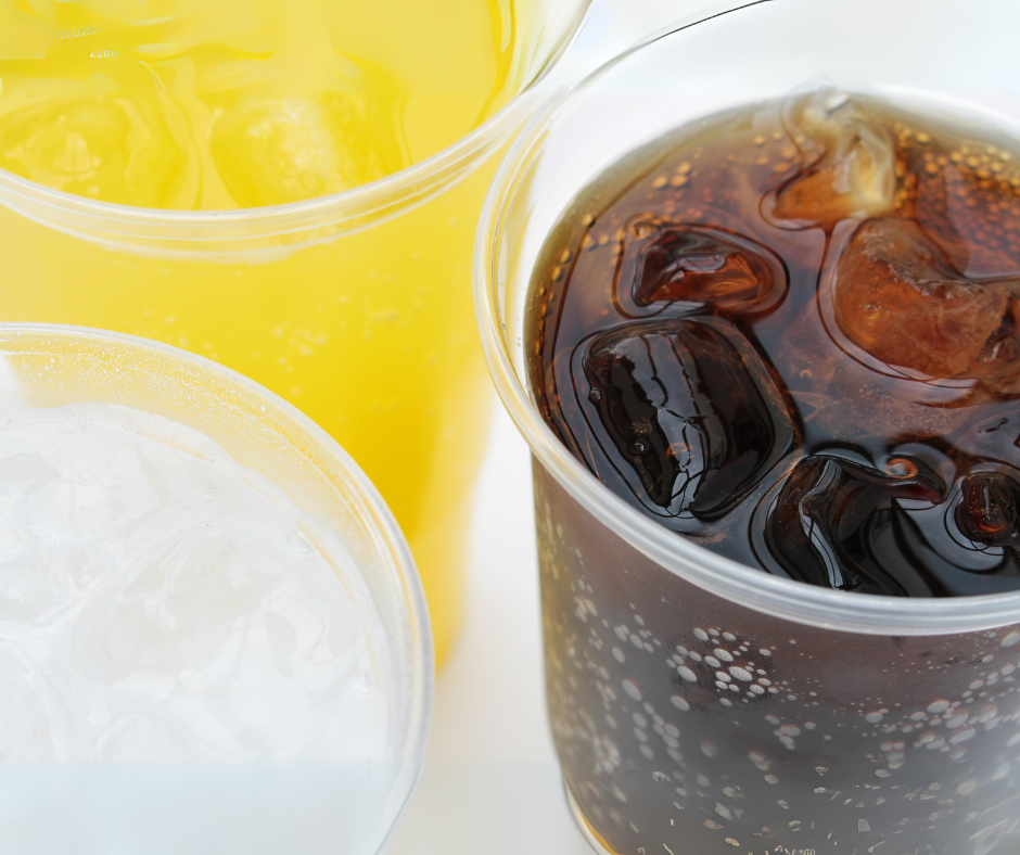 Three cups of different carbonated beverages with ice cubes from top view - clear soda, orange juice, and cola.