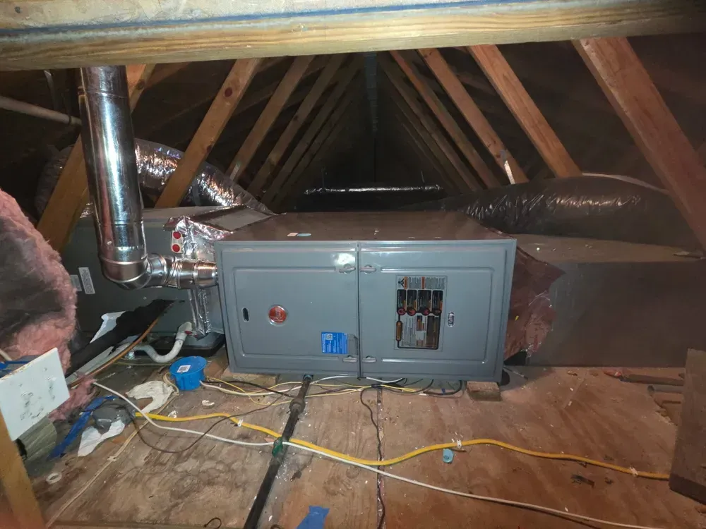 HVAC unit in an attic with ductwork, electrical wiring, and wooden beams.