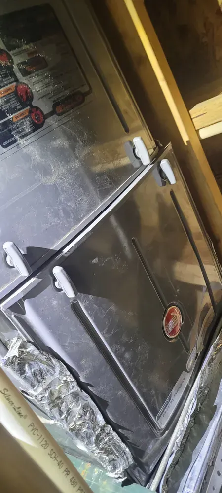 An air handler inside a wooden frame, featuring a metallic panel and a Rheem logo.